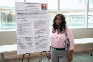 Damidera David-Olusa stands next to her poster at the Golub Fellows Symposium